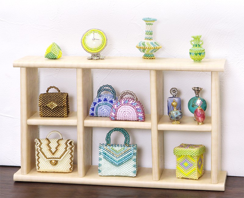 Miniature beaded bags displayed on a small open cabinet