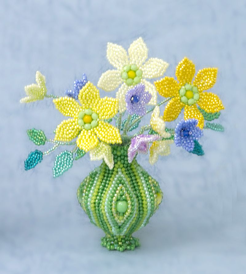 Green striped vase with a bunch of yellow and purple flowers